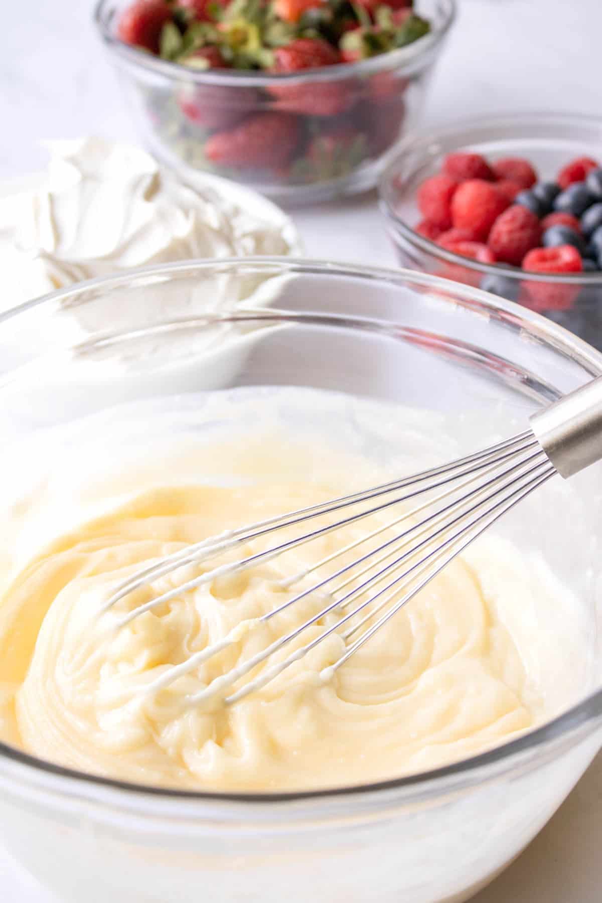 A bowl with a cheesecake dip batter and a whisk.