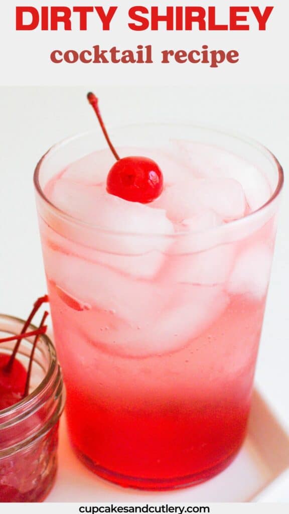 Close up of a red cocktail in a glass of ice topped by a cocktail cherry.