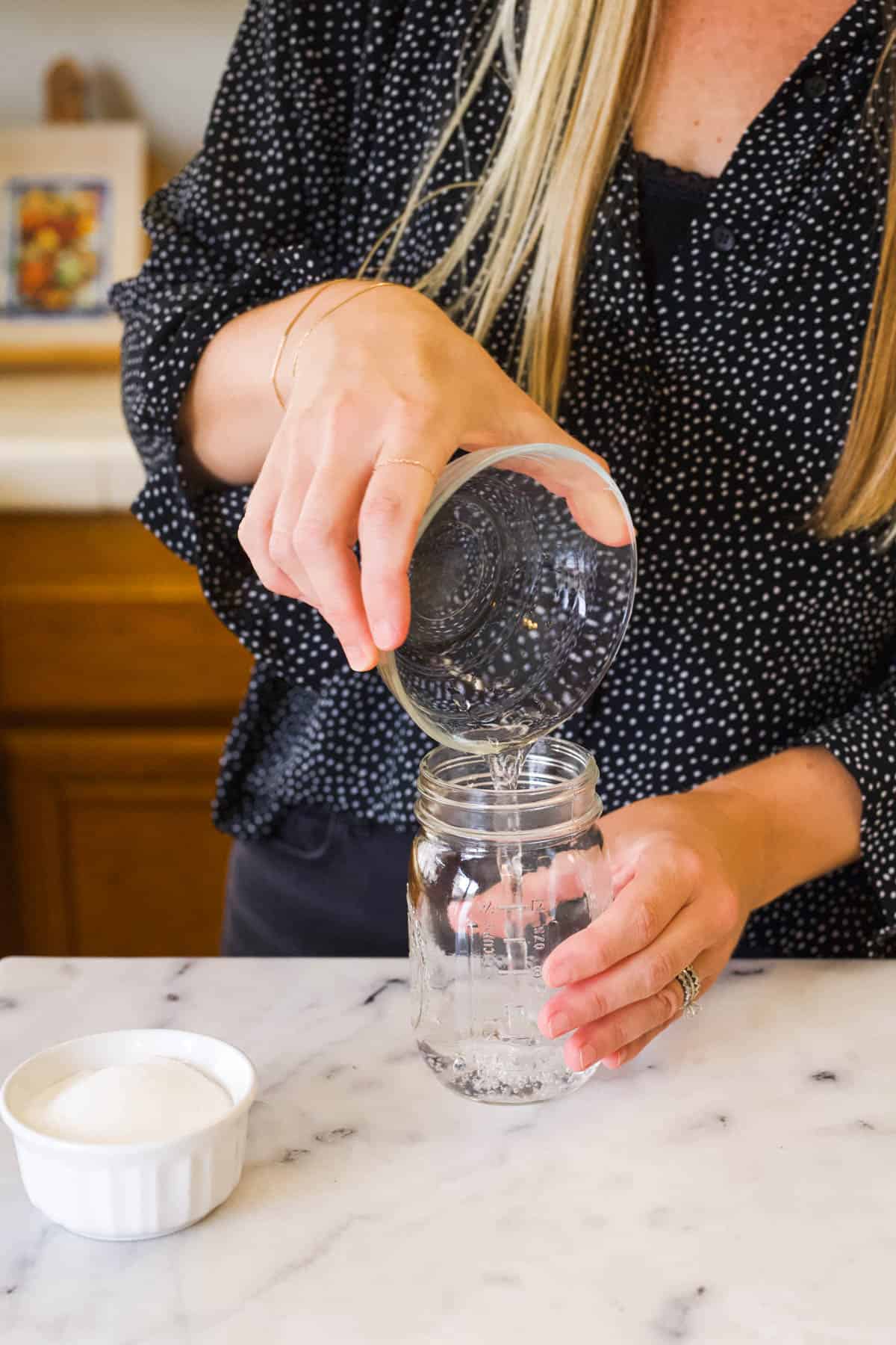 Woman pouring water into a mason jar.