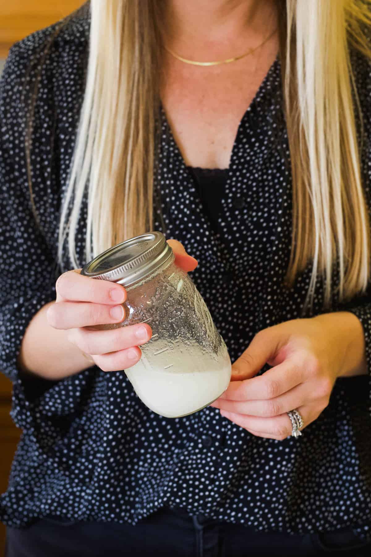 Woman shaking a jar of sugar and water to make simple syrup.