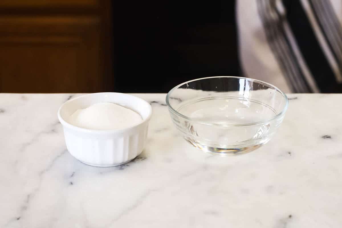 Bowls of sugar and water on a white marble countertop.