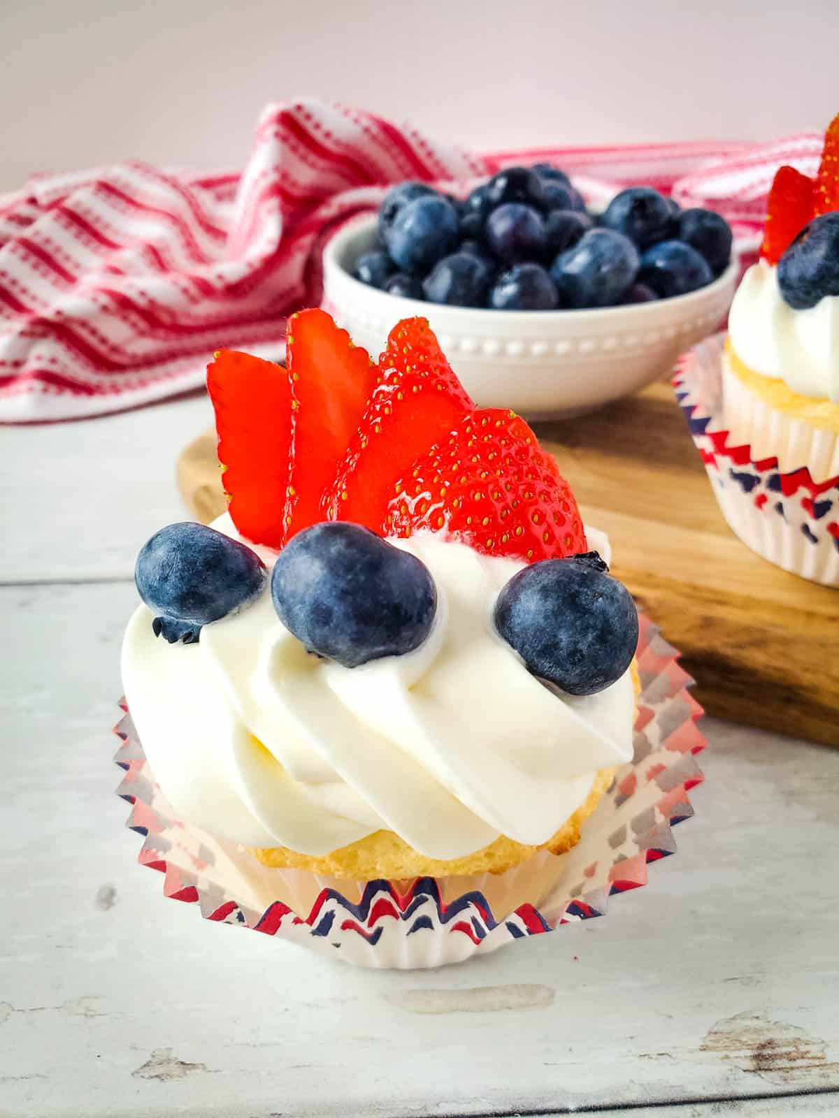 Patriotic angel food cake cupcakes that are red white and blue from berries and frosting.