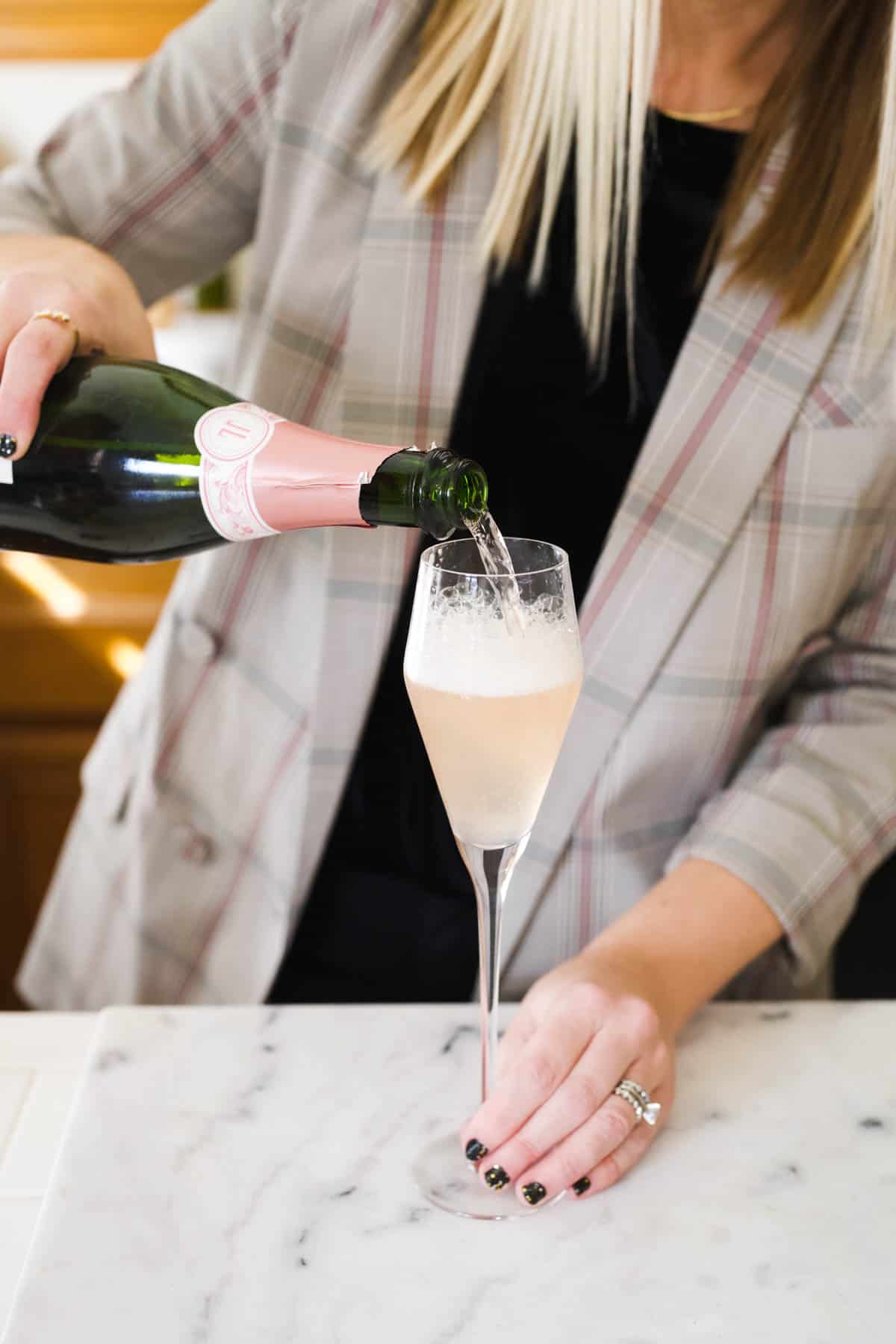 Woman pouring pink champagne into a flute.