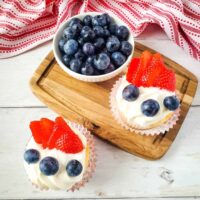White frosted angel food cake cupcakes topped with blueberries and strawberries for fourth of july.