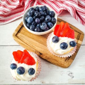 White frosted angel food cake cupcakes topped with blueberries and strawberries for fourth of july.