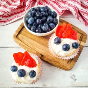 White frosted angel food cake cupcakes topped with blueberries and strawberries for fourth of july.