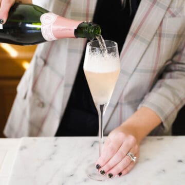 Woman topping up a champagne flute with pink champagne.