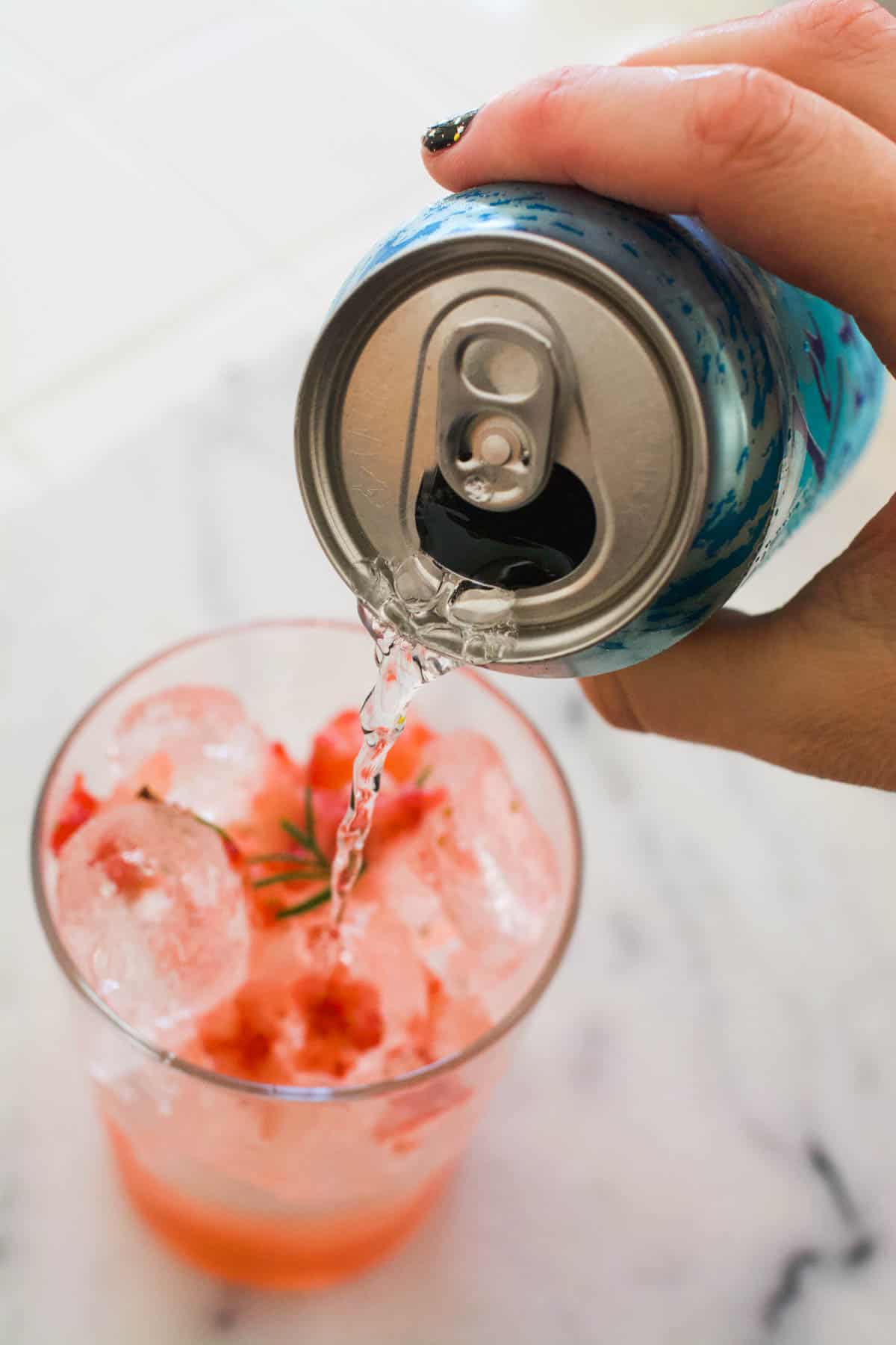 Topping off a strawberry mocktail for summer with sparkling water.