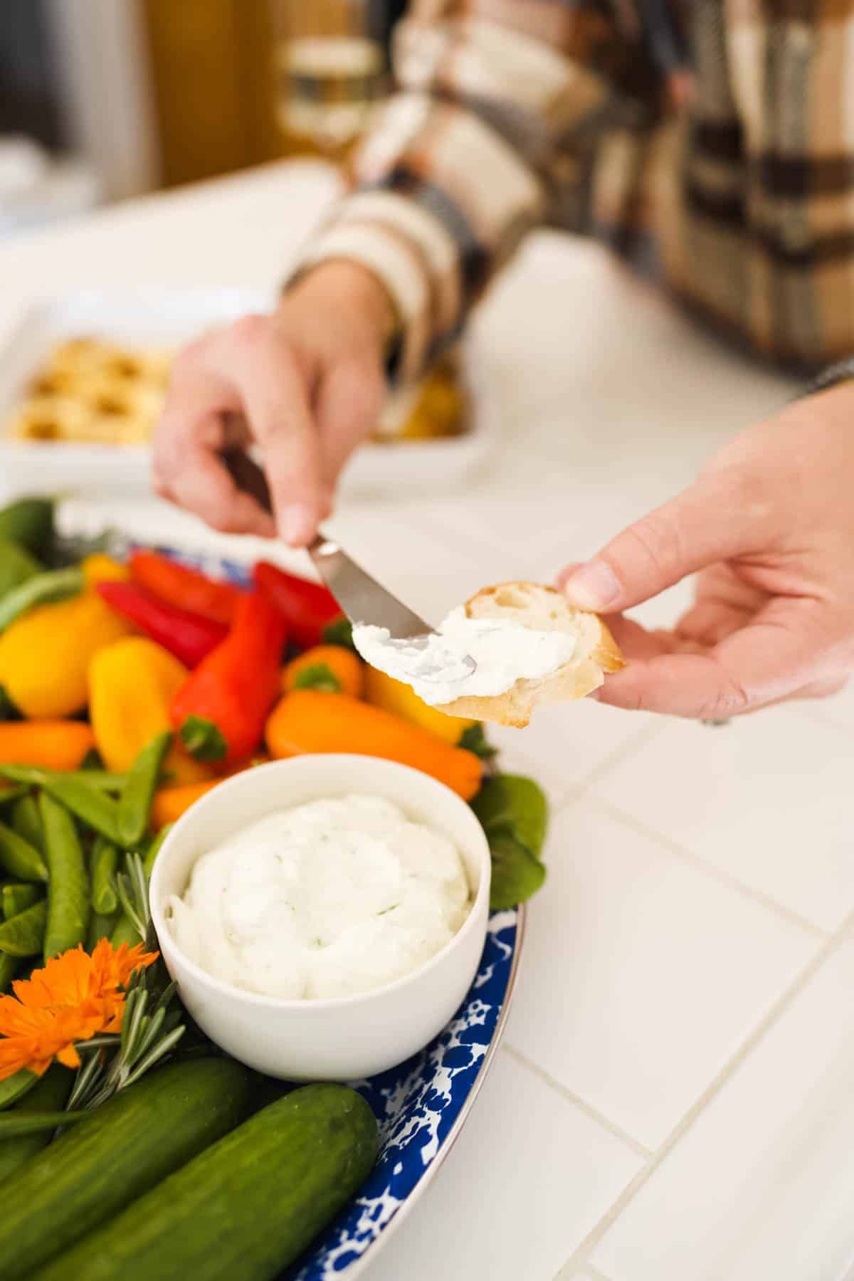 Woman spreading dip on a slice of baguette.