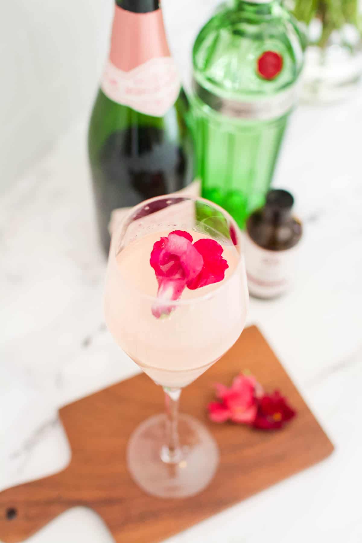 Close up of a Lavender French 75 with a pink edible flower floating in the top of the champagne flute.