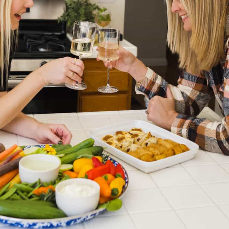 A Chicks and dips themed girls night with 2 woman clinking wine glasses.