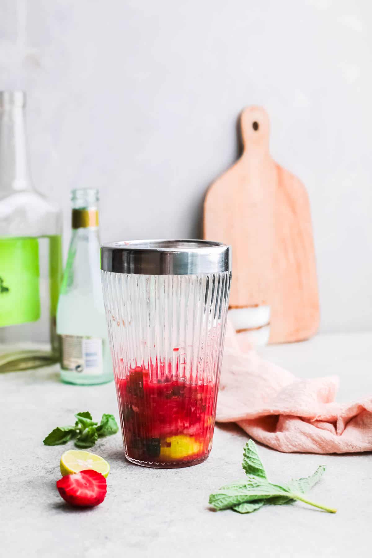 Fresh fruit muddled in a glass cocktail shaker.