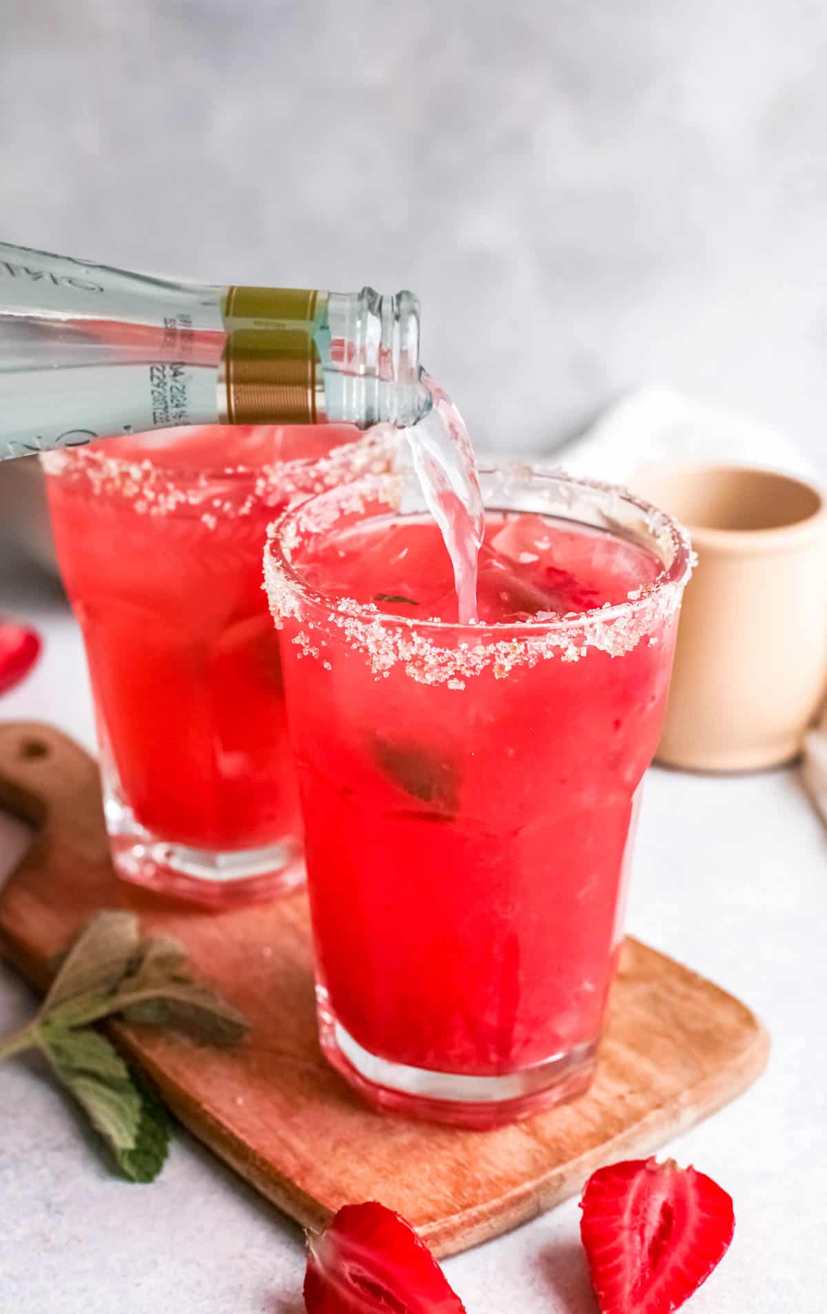 Strawberry cocktails being topped up with ginger beer.
