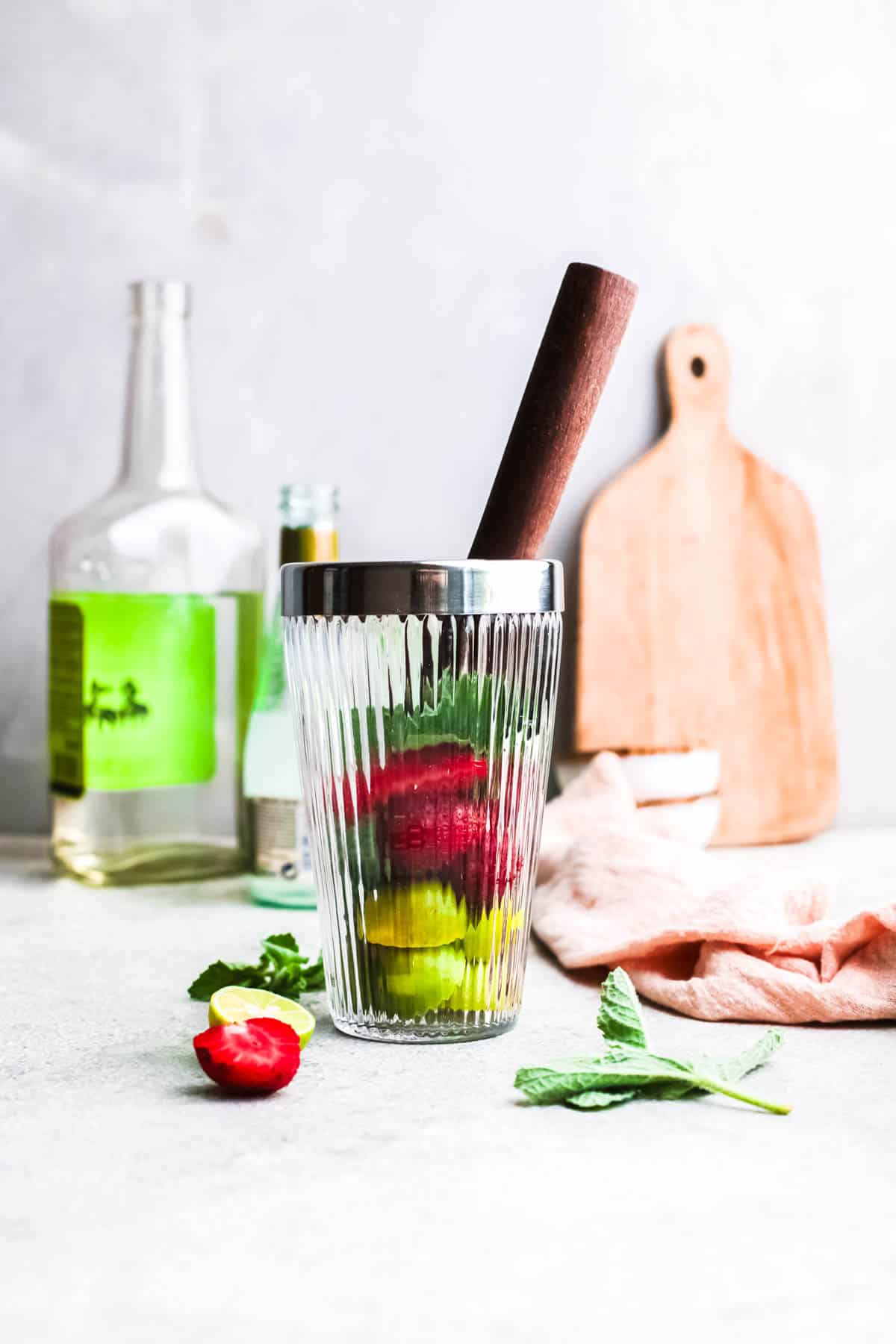 Fresh fruit in a cocktail shaker with a wooden muddler.