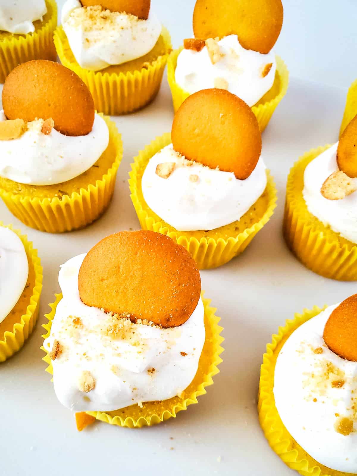 A batch of banana pudding cupcakes on a white counter top.