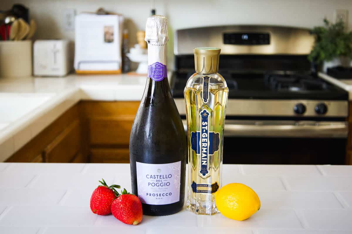 Ingredients to make an elderflower cocktail with strawberry and prosecco.