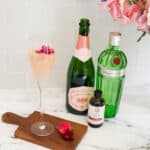 Lavender French 75 in a champagne flute with the bottles that made it in the background.