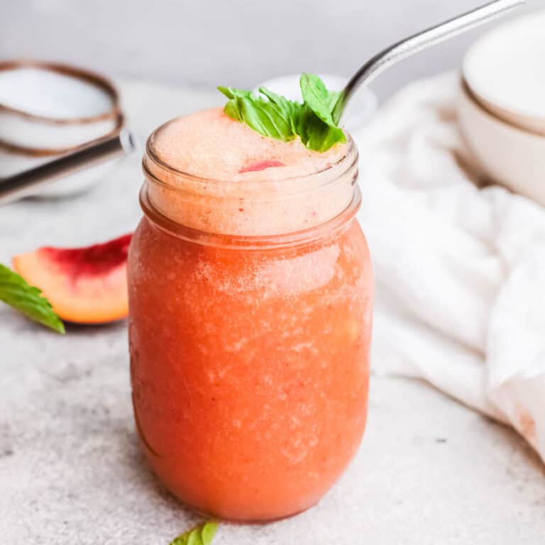 Closeup of peach frozen in a jar garnished with a sprig of fresh mint.