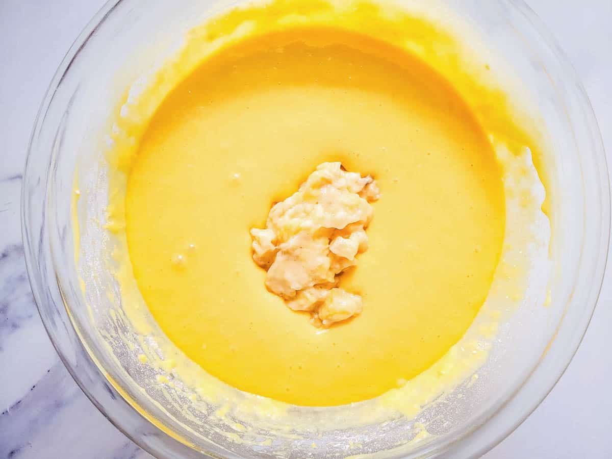 Adding the mashed banana to the cake batter.