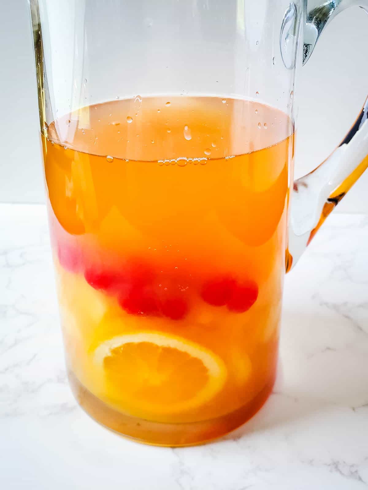 A close up of a pitcher full of sangria with rum and fresh fruit.