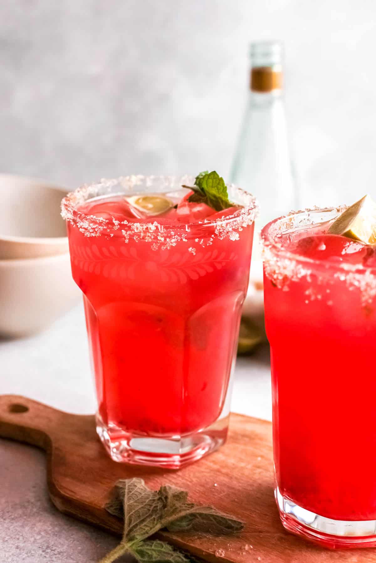 Strawberry cocktails in high ball glasses with a bottle of ginger beer in the background.