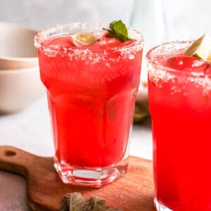 Close up of a strawberry cocktail garnished with lime and mint.