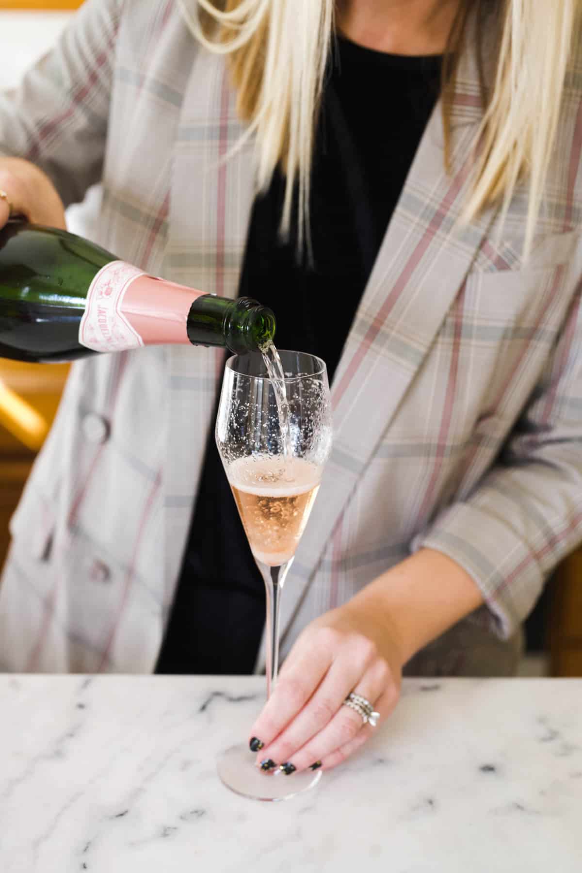 Woman pouring pink champagne into a flute.