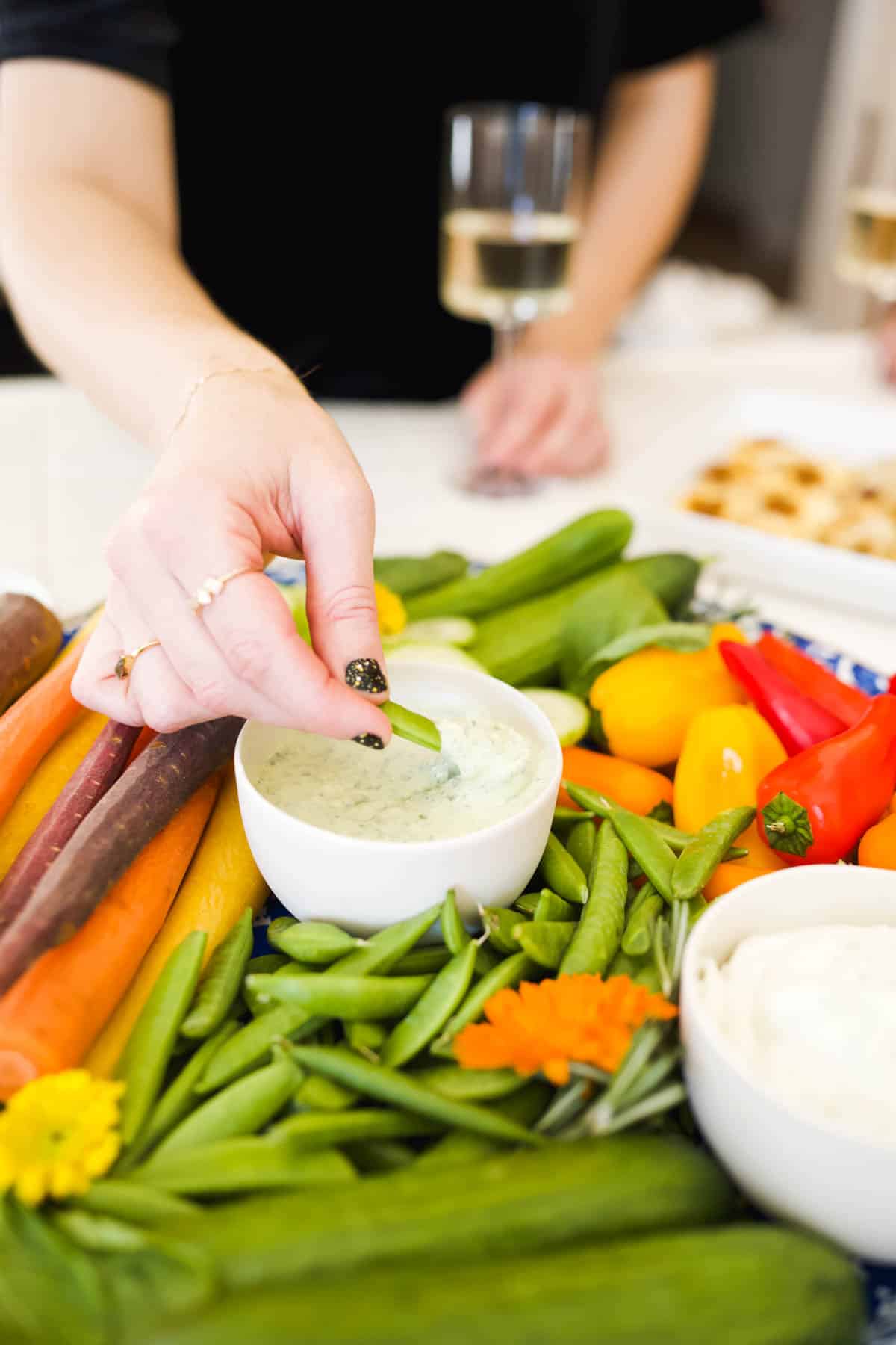 A woman dipping a veggie in a dip at a party.