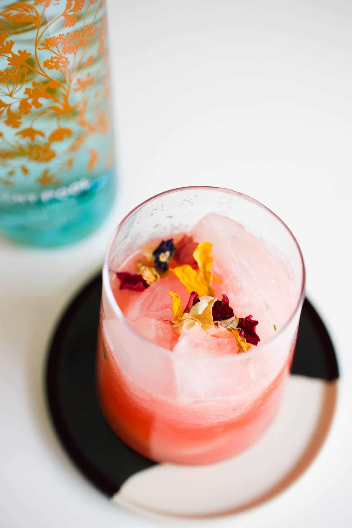 Watermelon juice and gin on the rocks garnished with edible flowers.
