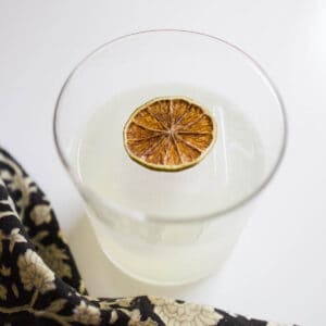 Close up of a dried lime wheel in a gin elderflower cocktail.