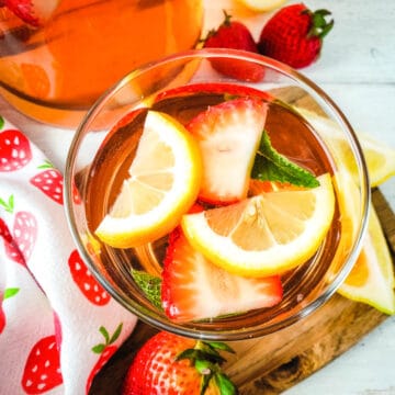 Overhead shot of a glass of Strawberry Rosé Sangria with sliced lemons and fresh mint leaves.