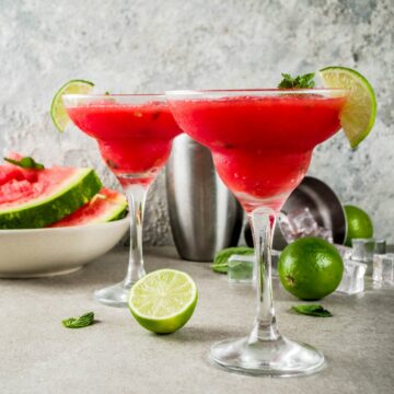 Margarita glasses holding vodka watermelon cocktails on a table.