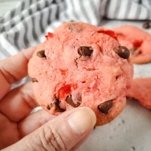 Woman holding a pink cookie made with cherry cake mix and chocolate chips.
