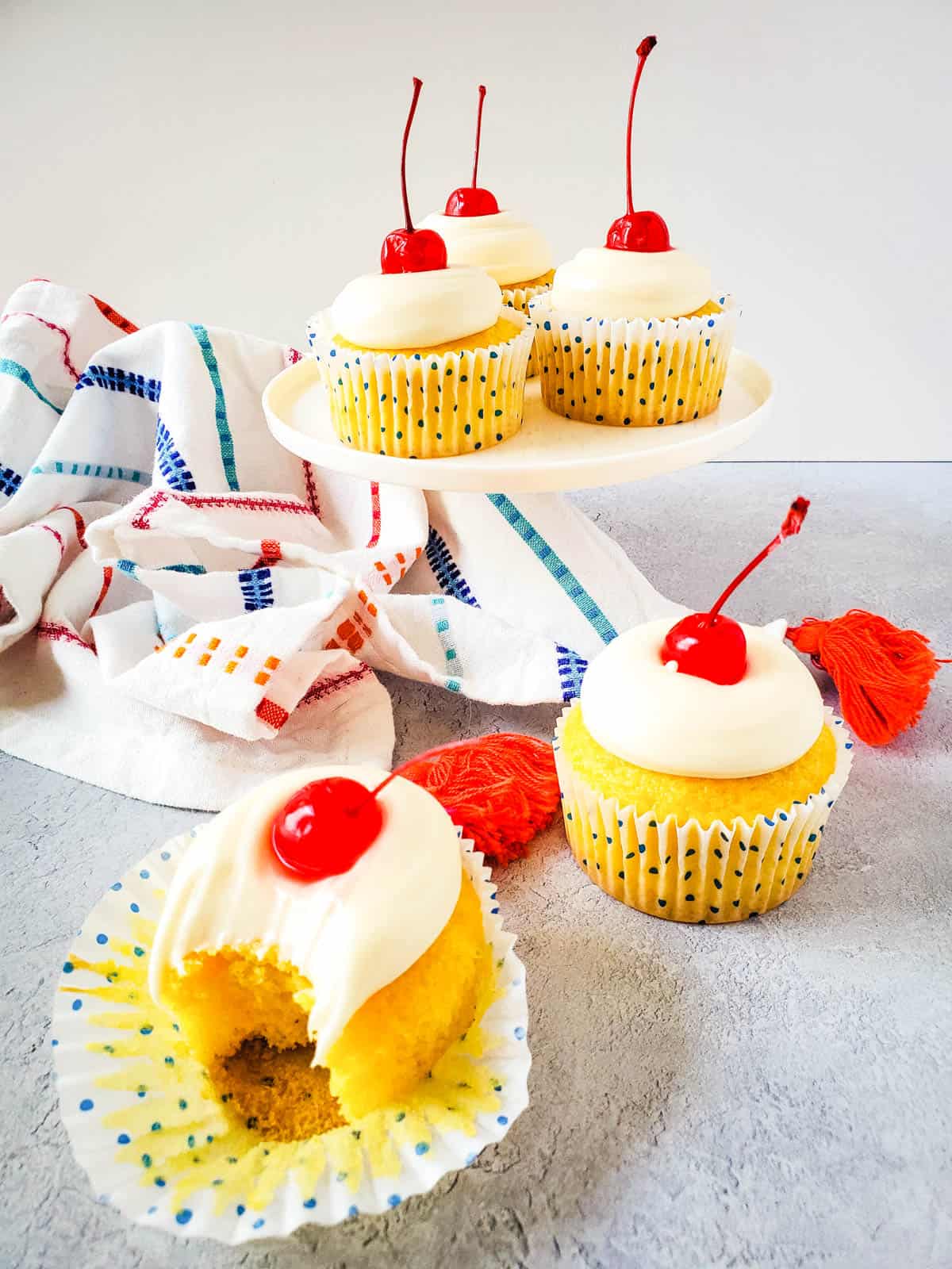 A bunch of coconut cupcakes on display with a kitchen towel at the background.
