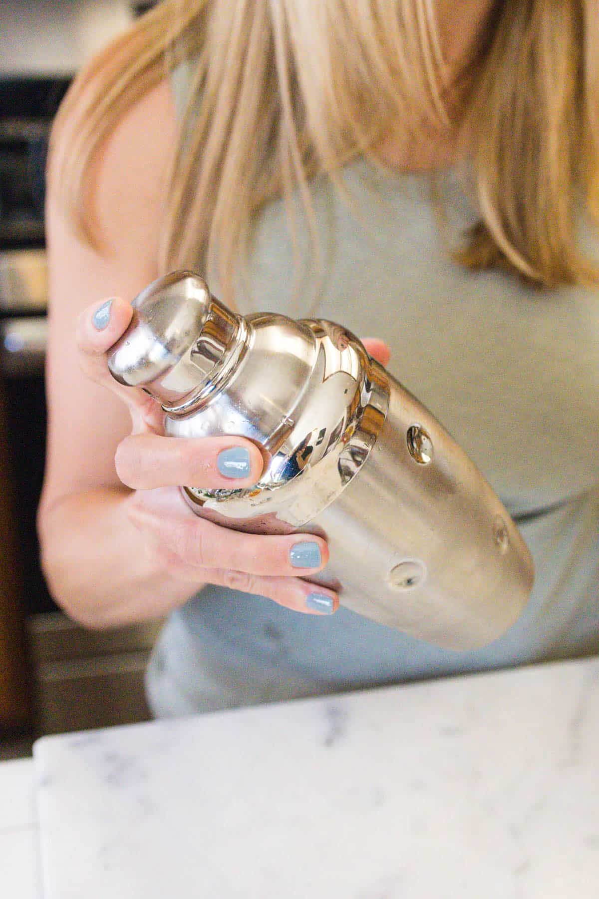Woman shaking a cocktail shaker.