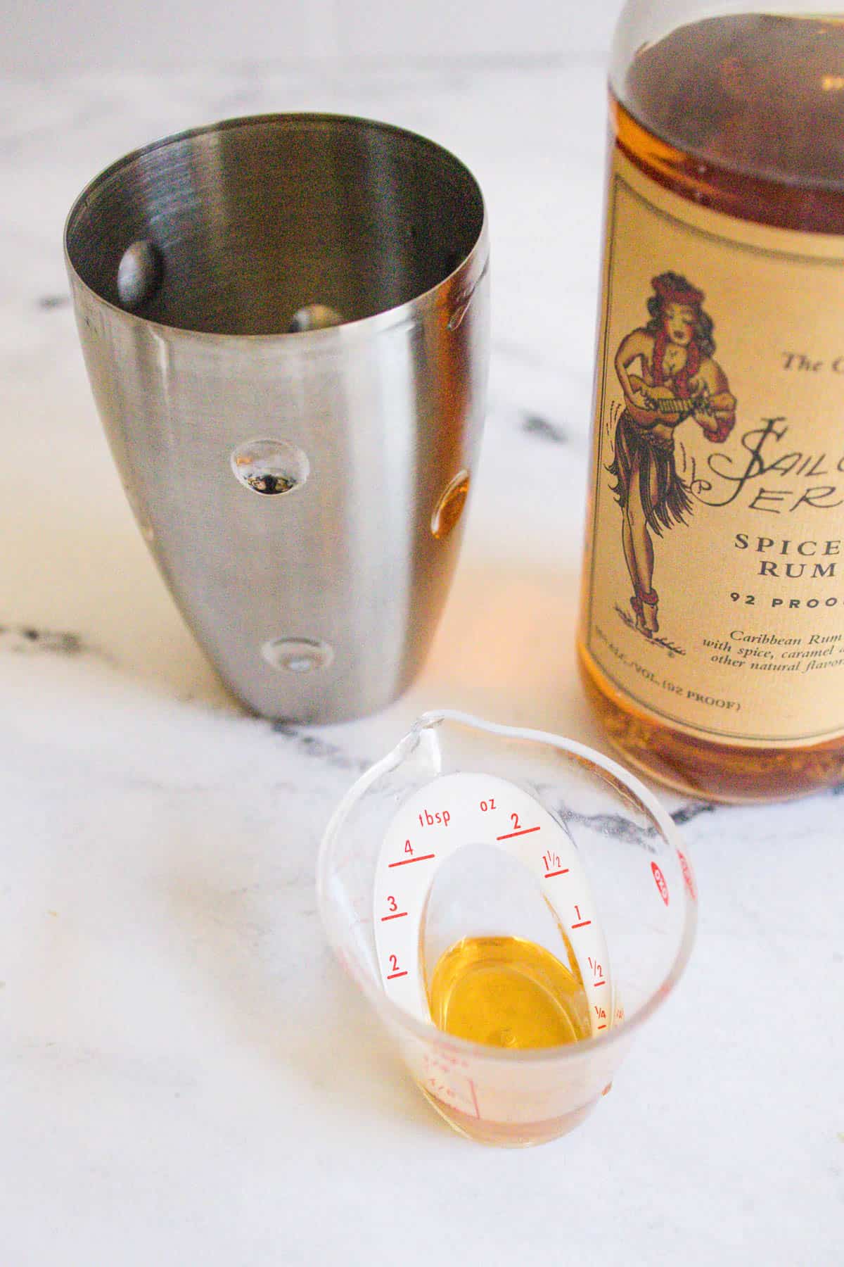 Spiced rum being measured into a cocktail shaker.