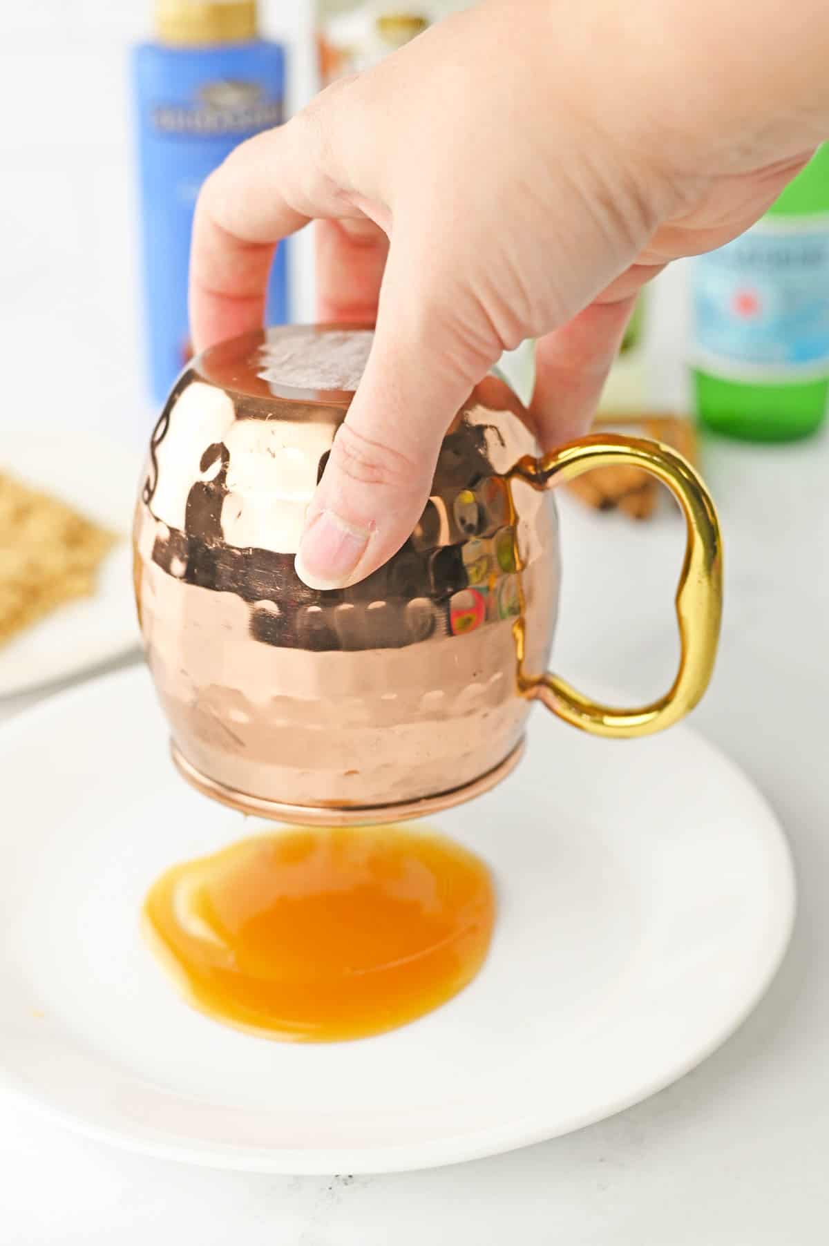 Dipping a copper mule mug in caramel sauce.