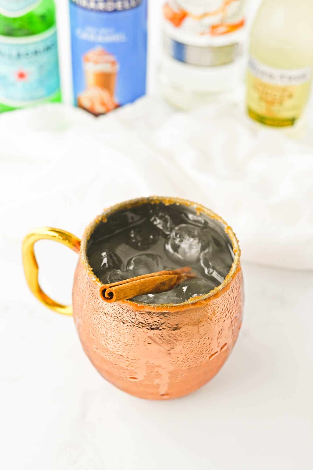 Caramel Vodka Moscow Mule garnished with a cinnamon stick in a mule mug. 