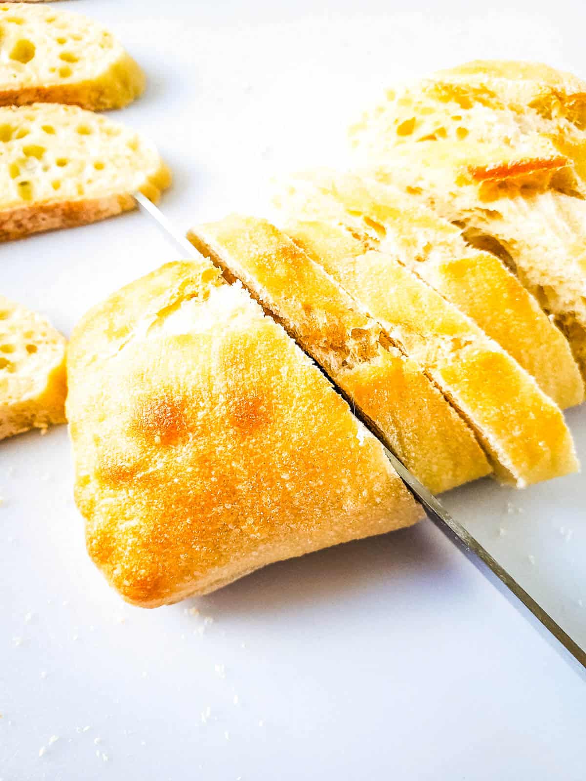 Slicing baguette bread for pimiento cheese crostini.