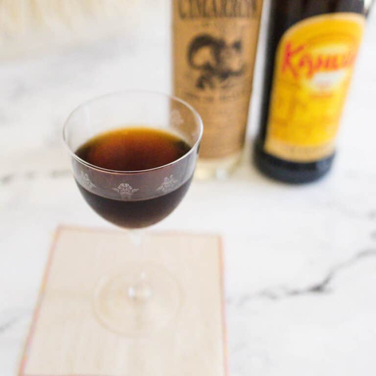 Espresso martini with bottles of tequila and Kahlua in the background.