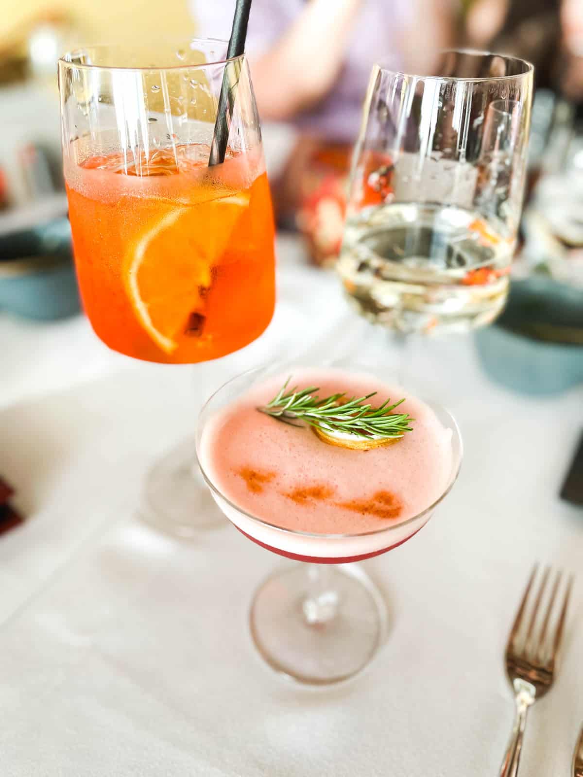 2 cocktails and a wine glass on a dining table inside Tocca Ferro in the JW Marriott Anaheim.