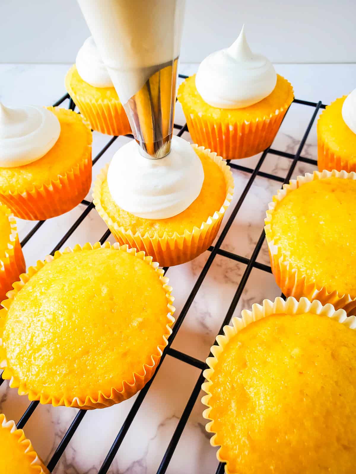 Piping rum infused frosting on pina colada cupcakes.