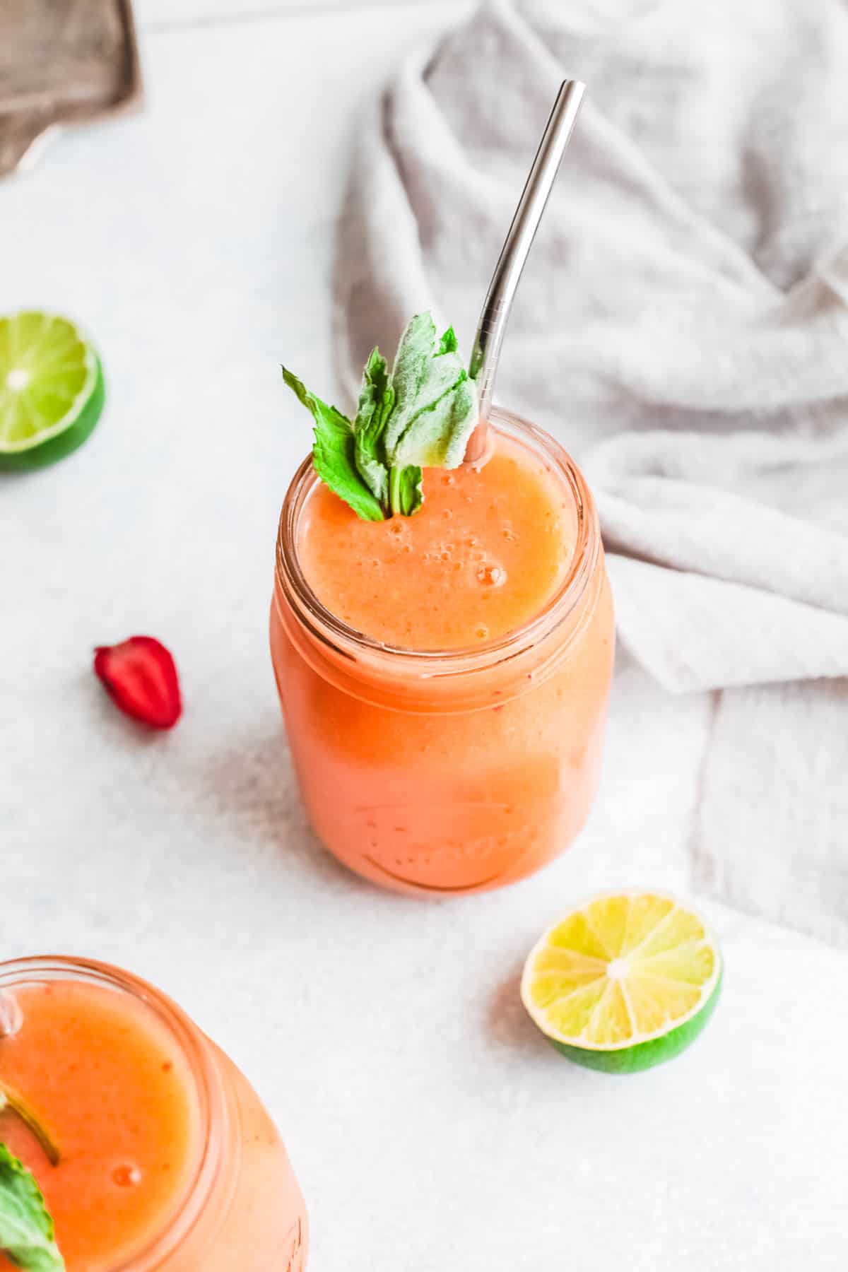 Frozen Strawberry Mango Daiquiri in a jar garnished with mint and a metal straw.