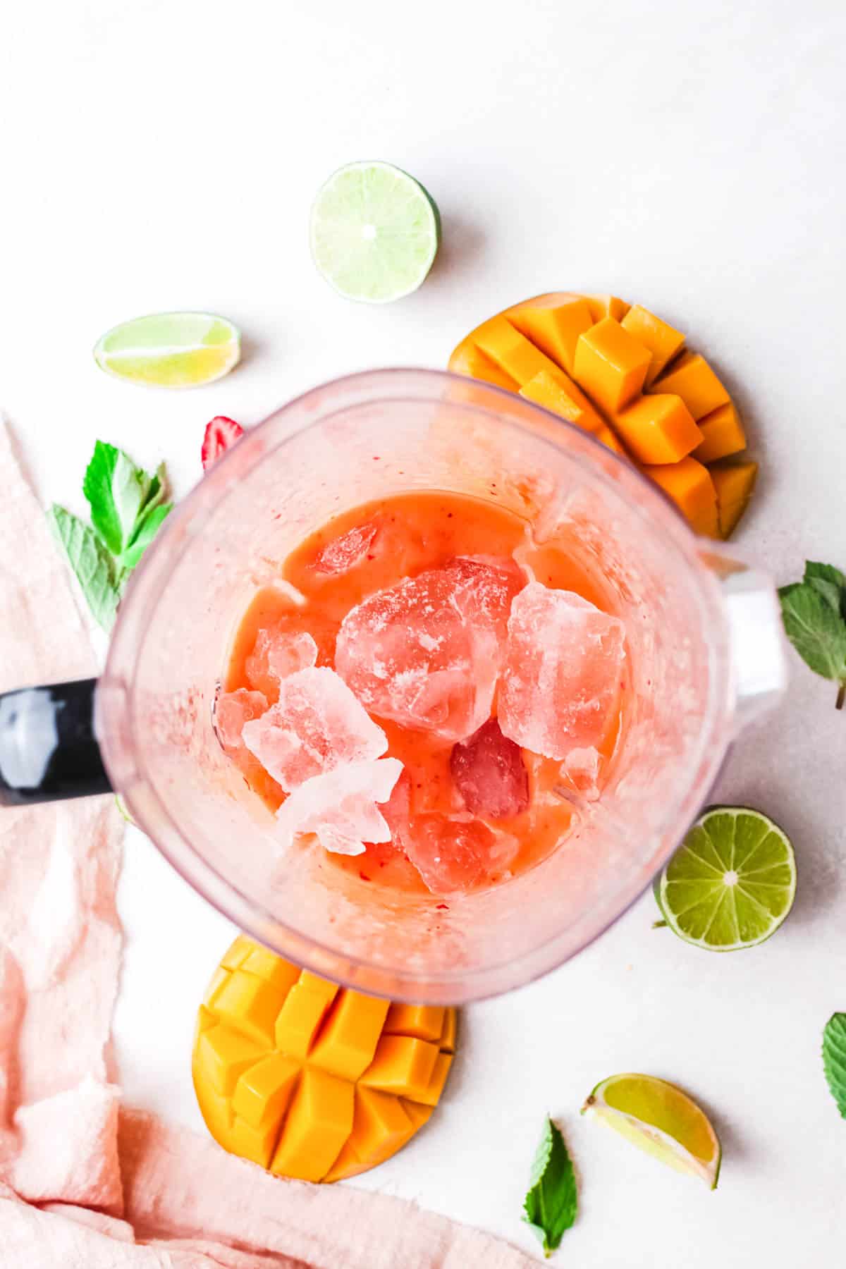 Adding ice to the blender with blitzed fruit for a frozen cocktail. 