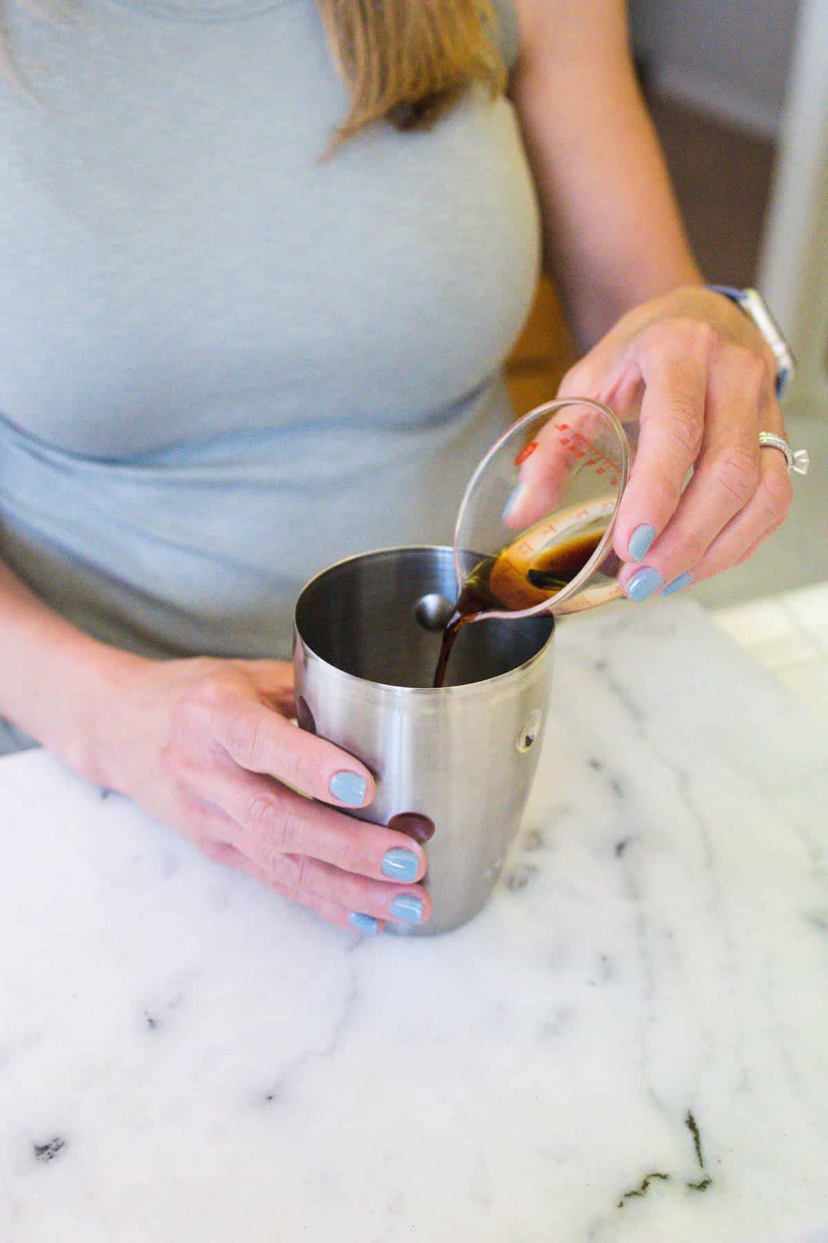 Pouring coffee liquor into a cocktail shaker. 