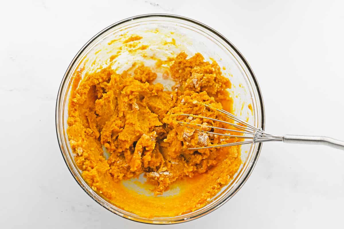 A mixing bowl with pumpkin puree and a whisk.
