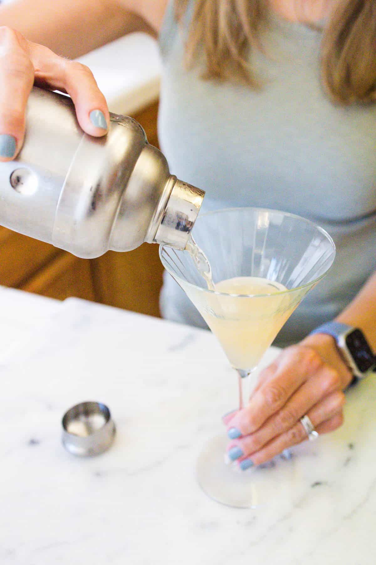 Woman straining a drink into a martini glass.