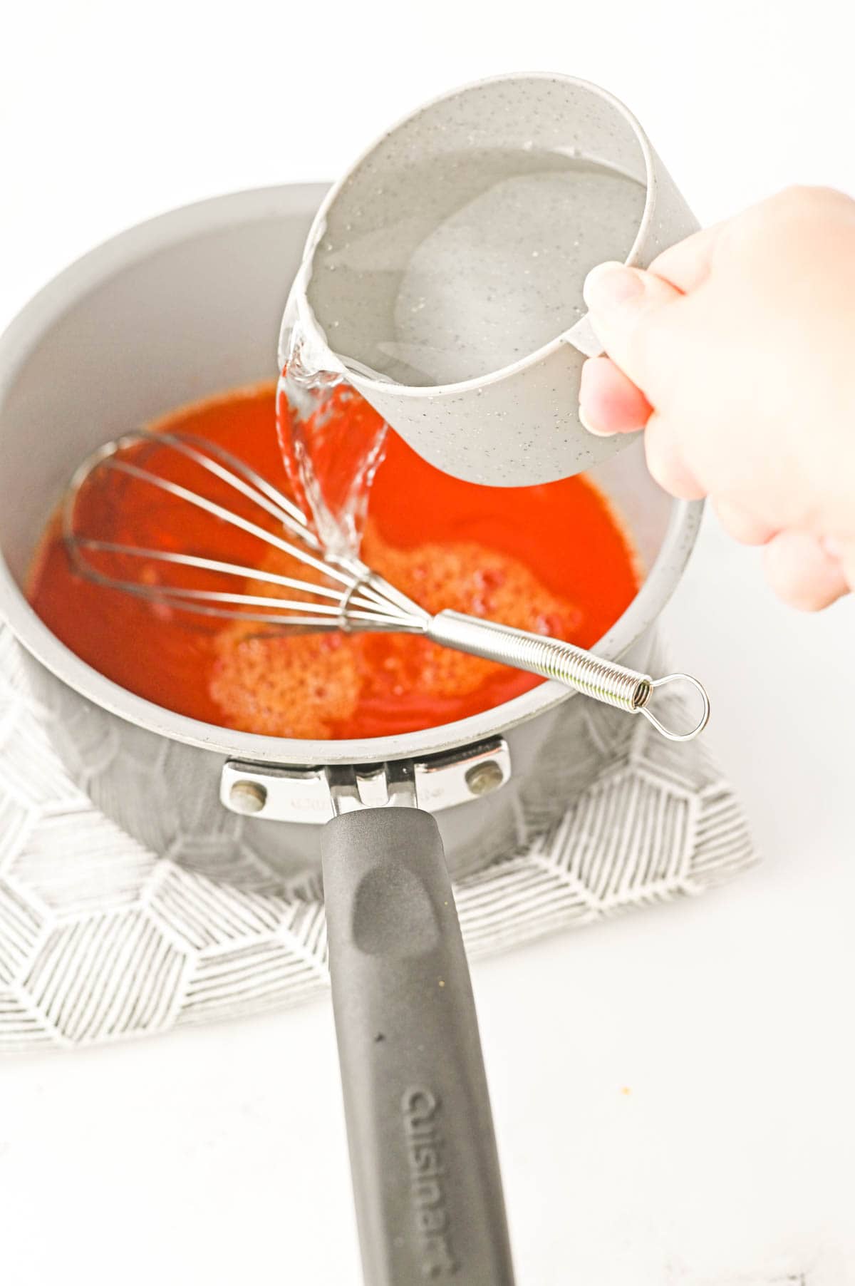 Cold water being poured into a pan of orange Jello.