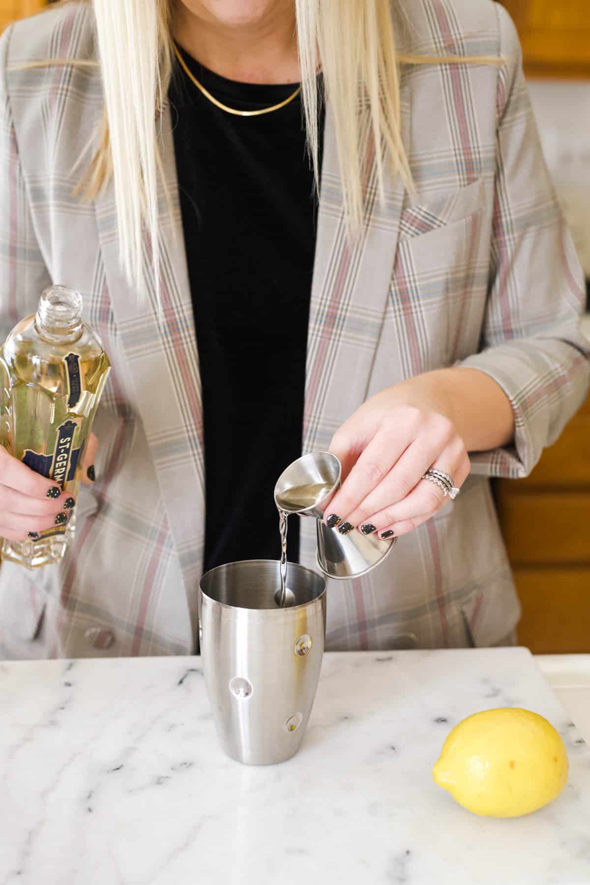 Woman adding St Germain to a cocktail shaker.