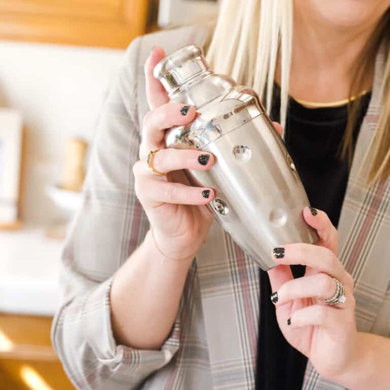 Woman holding up a silver cocktail shaker.